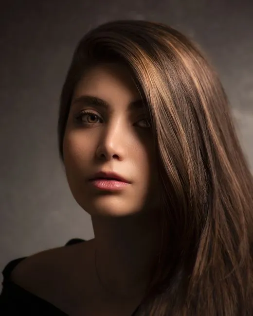 Elegant portrait of a young woman with long brunette hair and serene expression.
