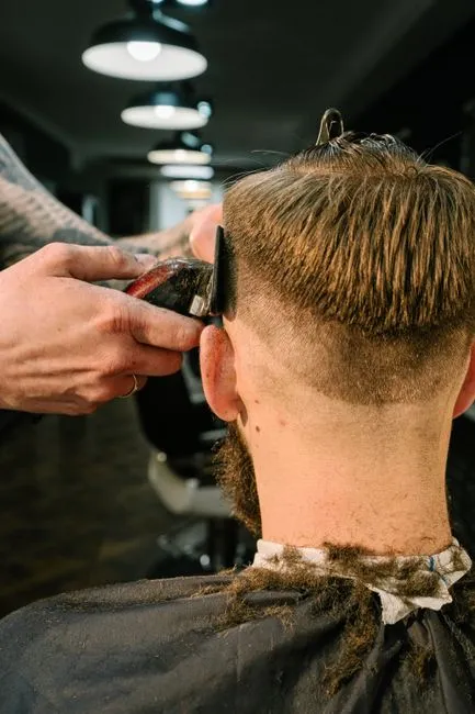 Barber performing a stylish haircut on a man in a modern barbershop.
